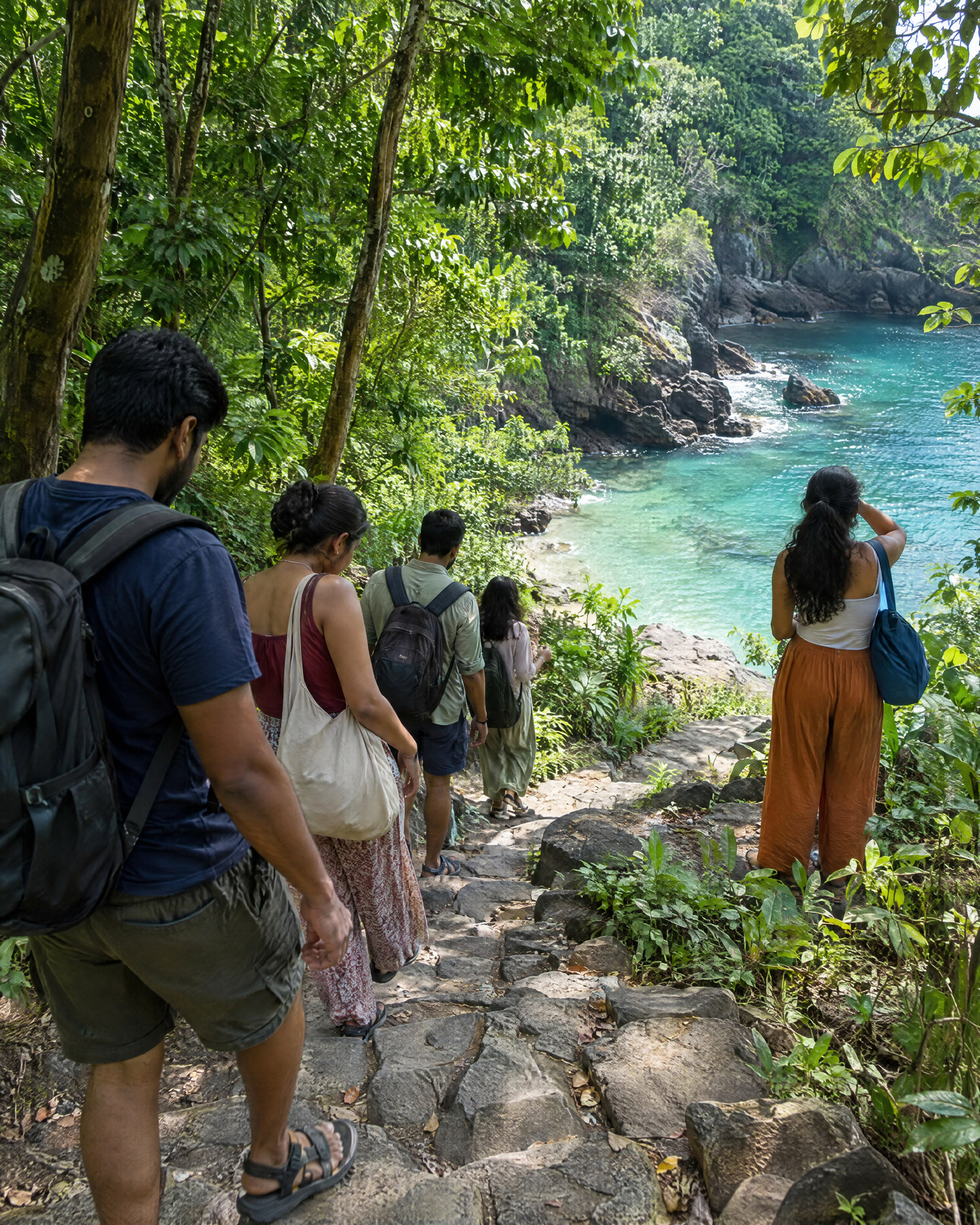 A local guide leading a few friends down stone steps through jungle to a hidden cove